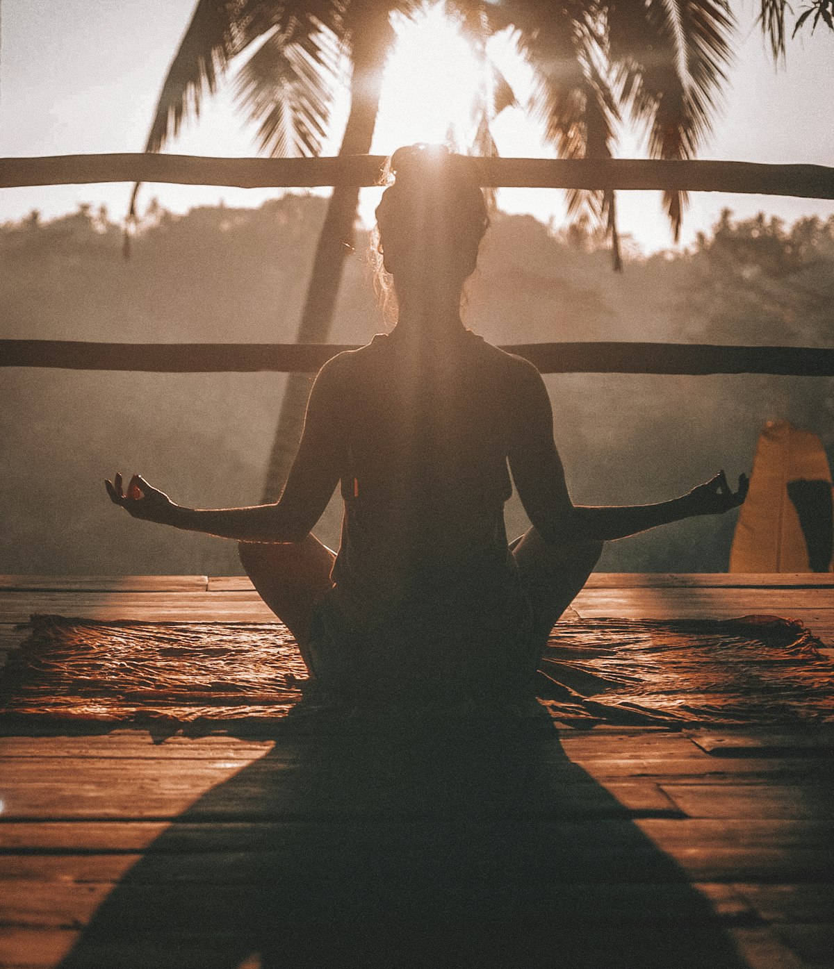 Person in mindful meditation posture beside calm waters at sunrise