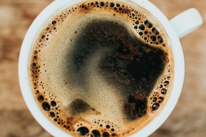 Commercial-grade chrome espresso machine extracting rich hazelnut crema into ceramic cup
