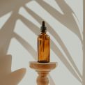 Luxury scented candle and architectural cold-air aroma diffuser on fluted travertine plinth